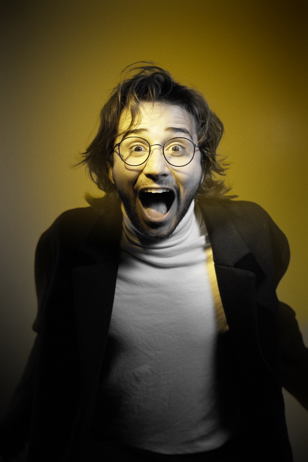 Wide-eyed portrait with an open mouth against a yellow-lit background.