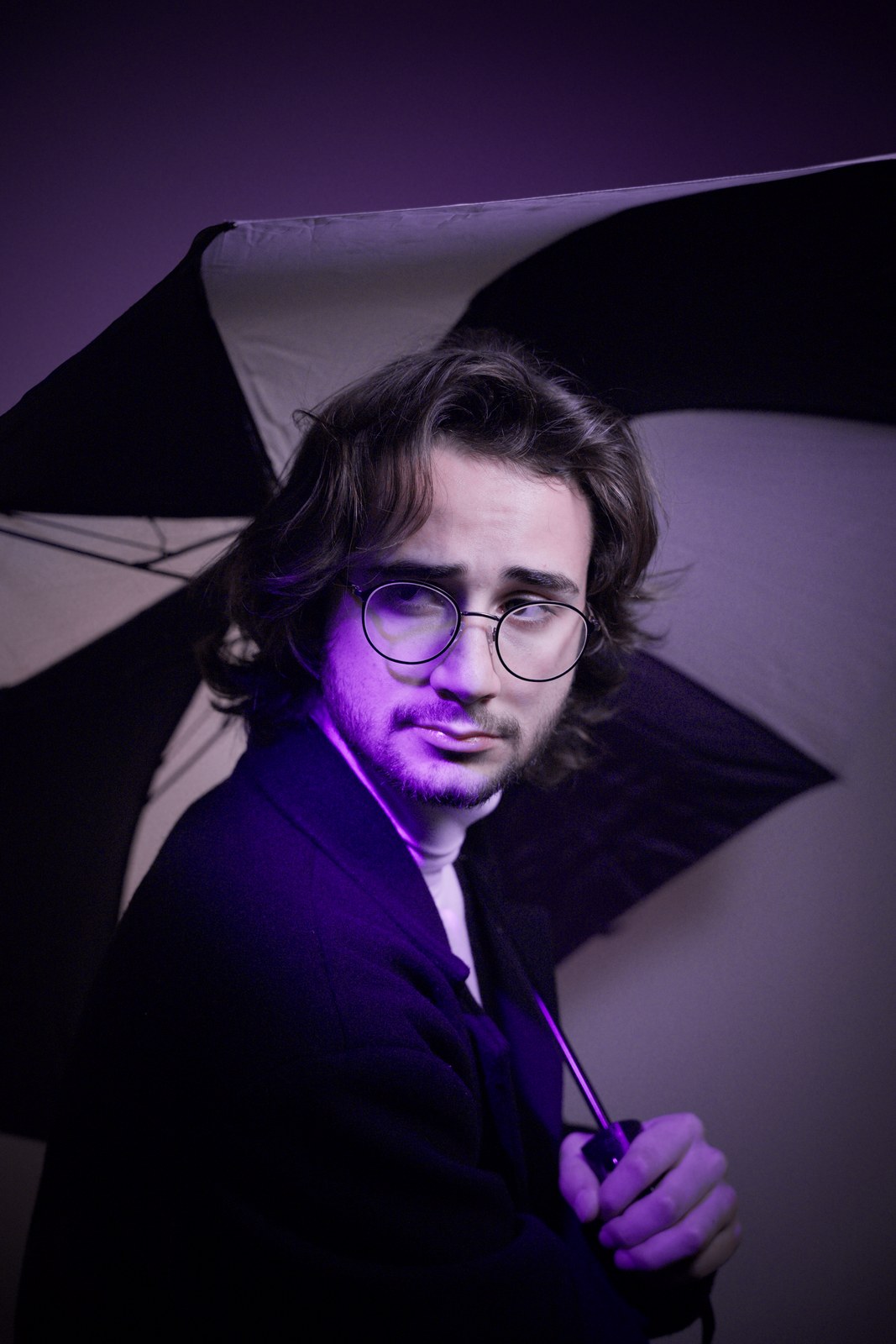 Portrait beneath an umbrella in violet light.