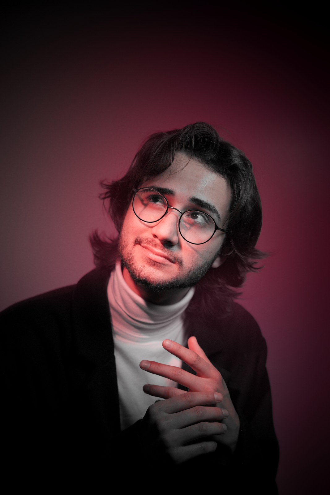Portrait looking upward in red light with a hand on the chest.