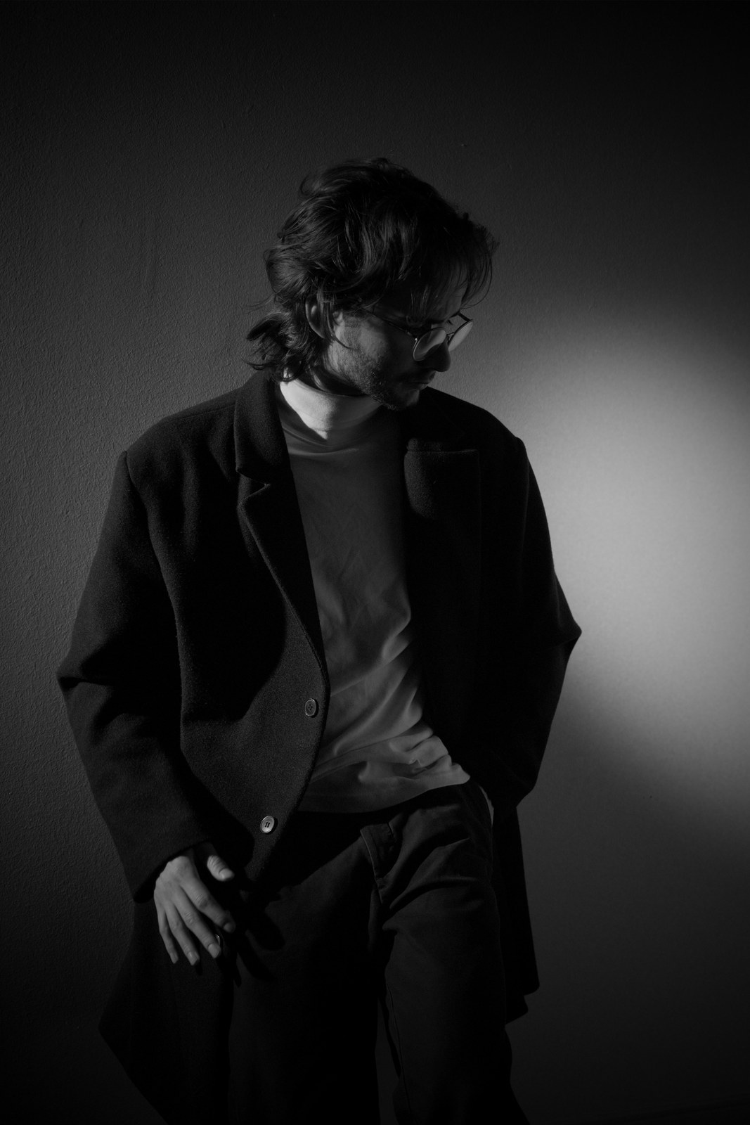Black-and-white portrait in a dark jacket with hands near the pockets.