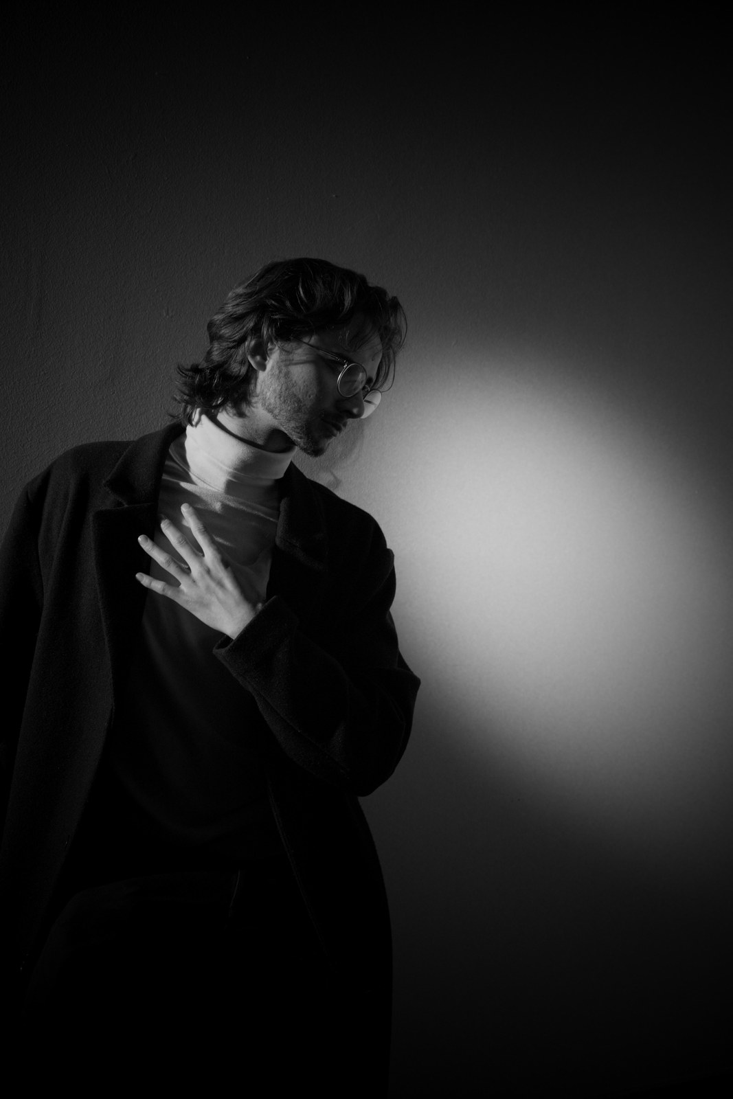 Black-and-white portrait with one hand against the chest.
