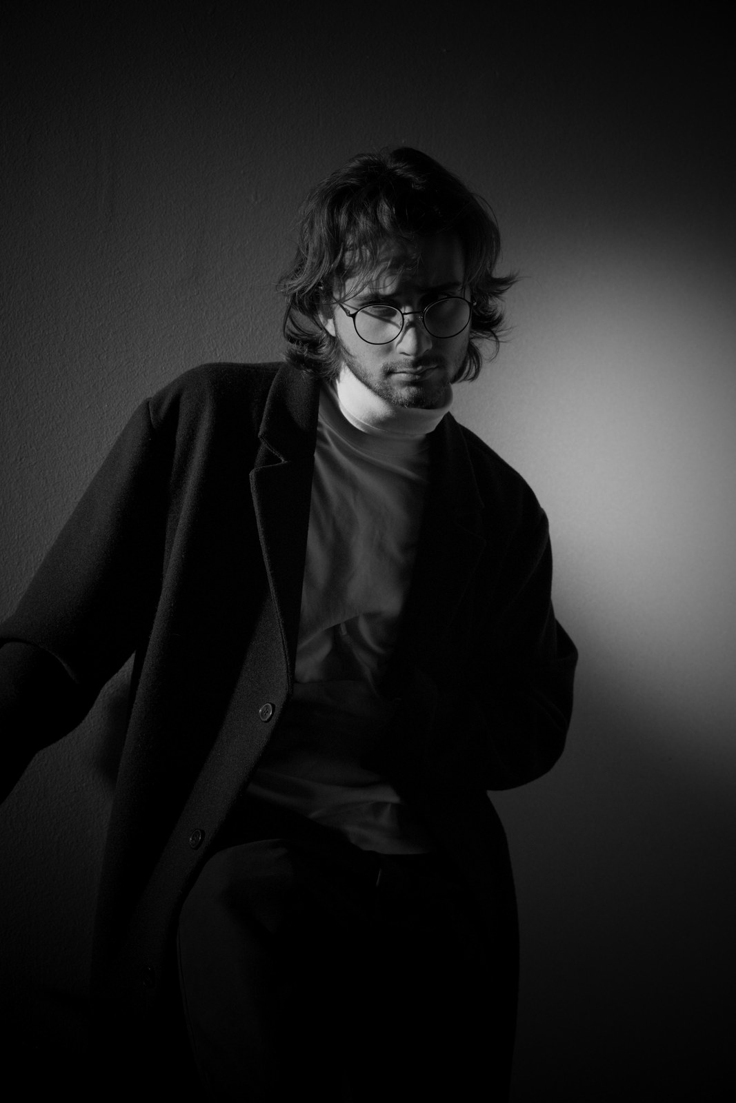 Black-and-white portrait leaning forward in a dark jacket.