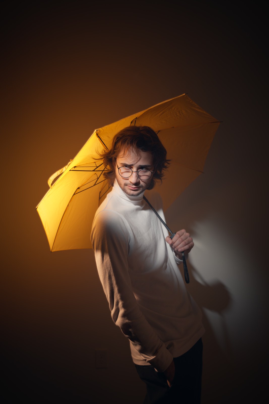 Portrait looking over one shoulder beneath a yellow umbrella.