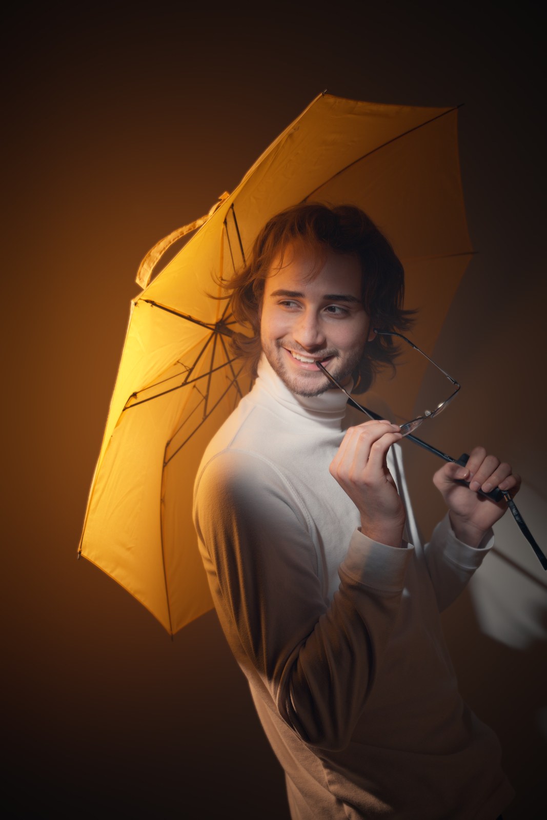 Portrait holding a yellow umbrella and smiling toward the camera.