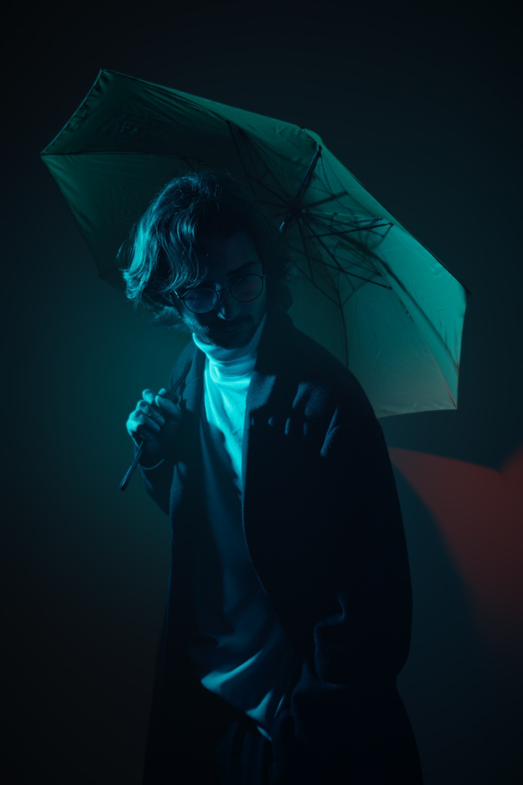 Side profile beneath an umbrella in teal light.