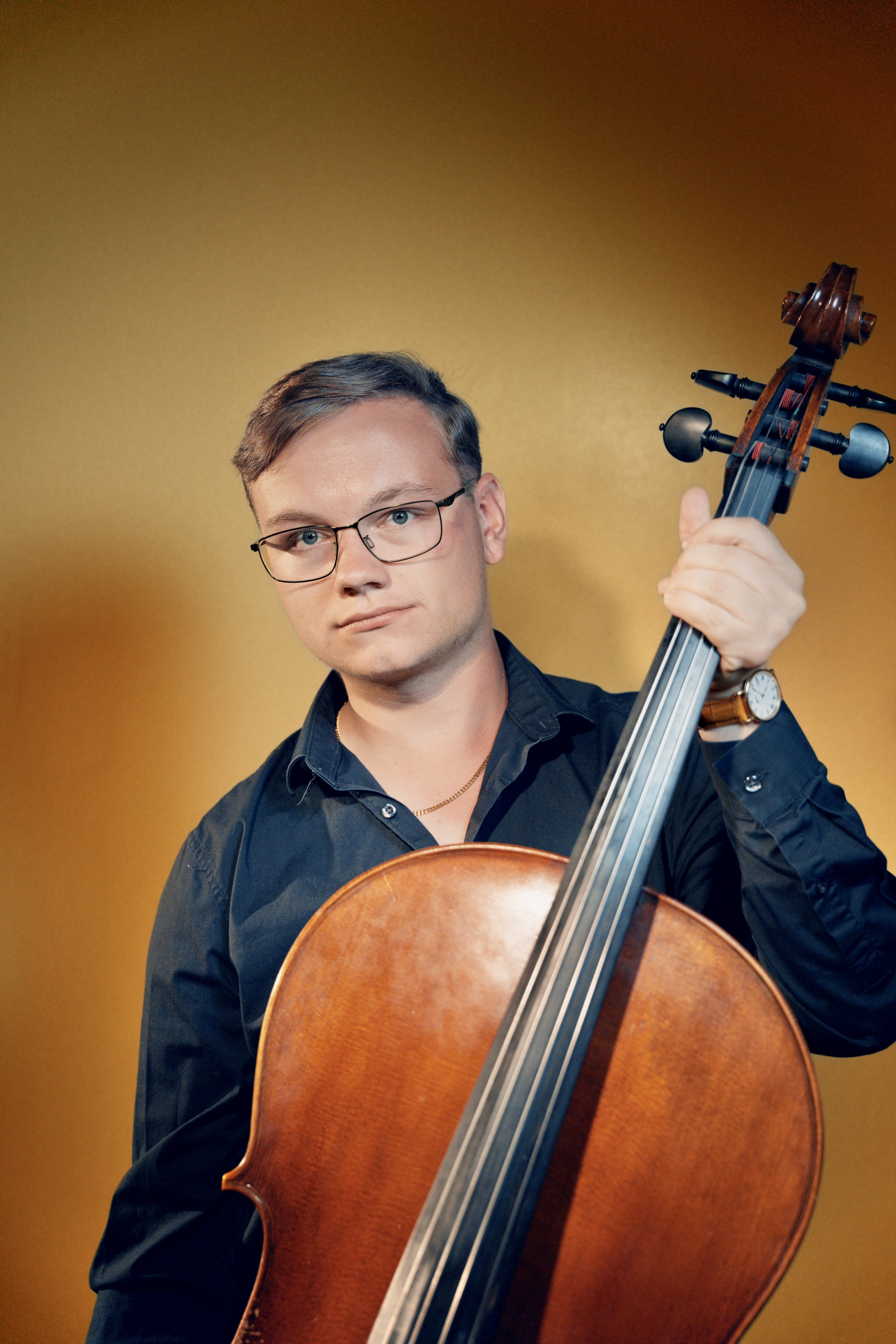 Will holding a cello against a warm gold backdrop